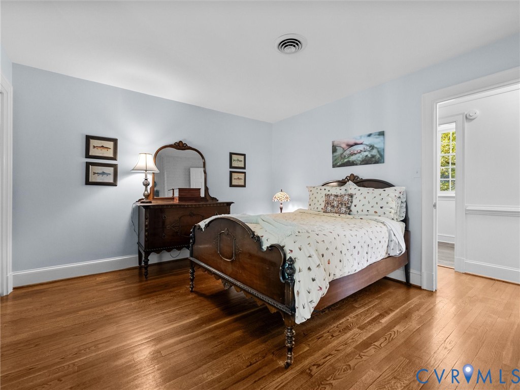Room featuring wood-finish flooring, neutral wall coloring, and millwork chair rail molding