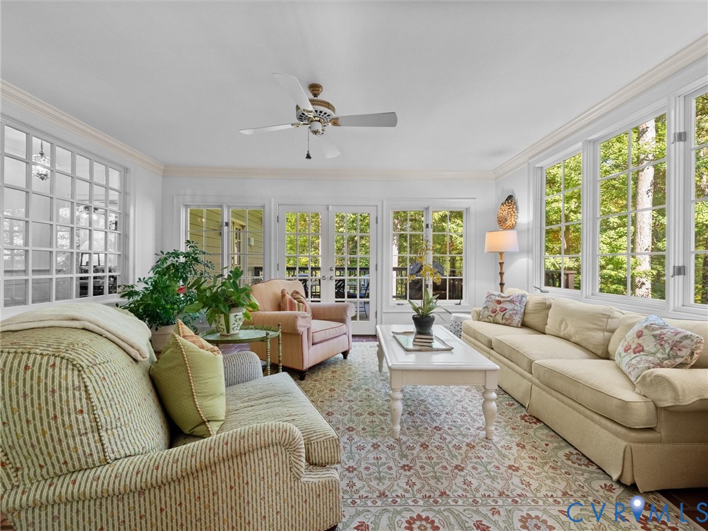 Sunroom featuring expansive multi-pane windows, glass-paneled double doors, crown molding, and a ceiling-mounted fan