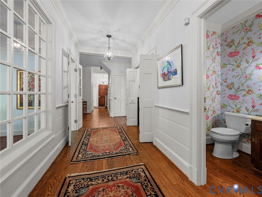 Hardwood flooring, crown molding, paneled wainscoting, glass-paned interior doors, and decorative wallpaper