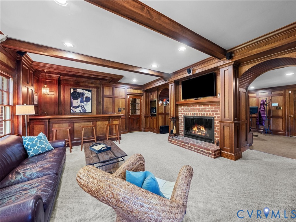 Extensive wood paneling featuring coffered ceiling beams, a built-in bar, a masonry brick fireplace, and arched doorways