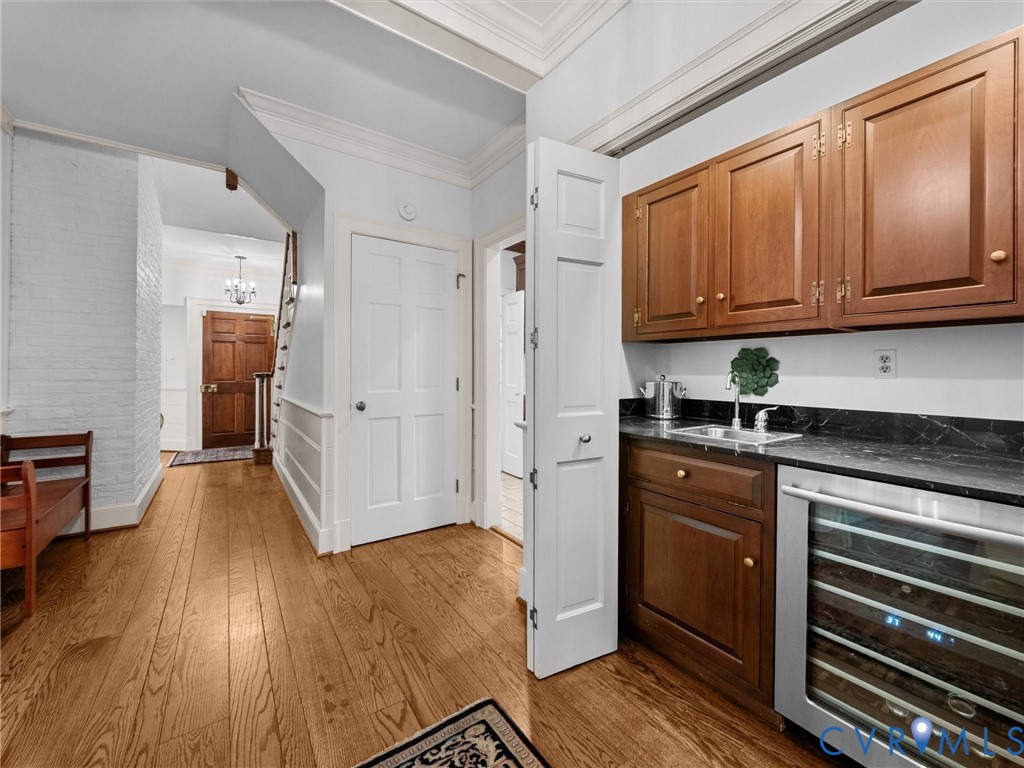 Wood-finish flooring, custom wood cabinetry, dark stone-finish countertops, built-in wine refrigeration, and white millwork detailing