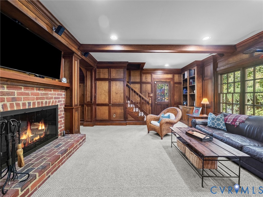 Custom wood-paneled walls, exposed ceiling beams, built-in shelving, brick fireplace surround, and multi-pane windows