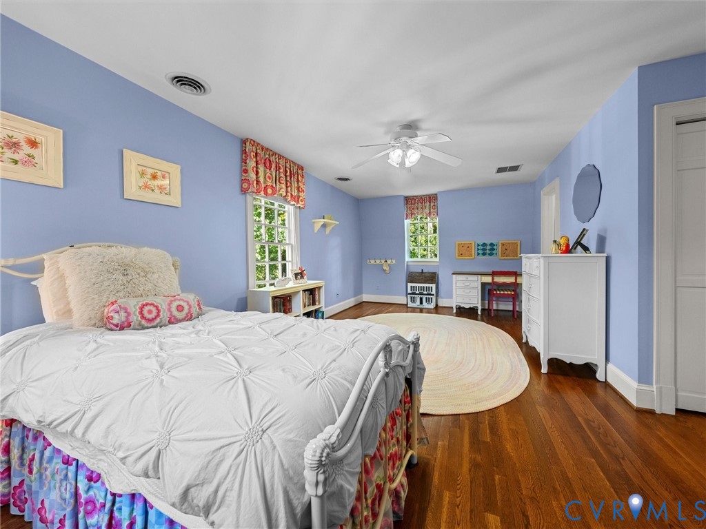 Wood-finish flooring, dual windows with decorative valances, and a ceiling-mounted light fixture with fan