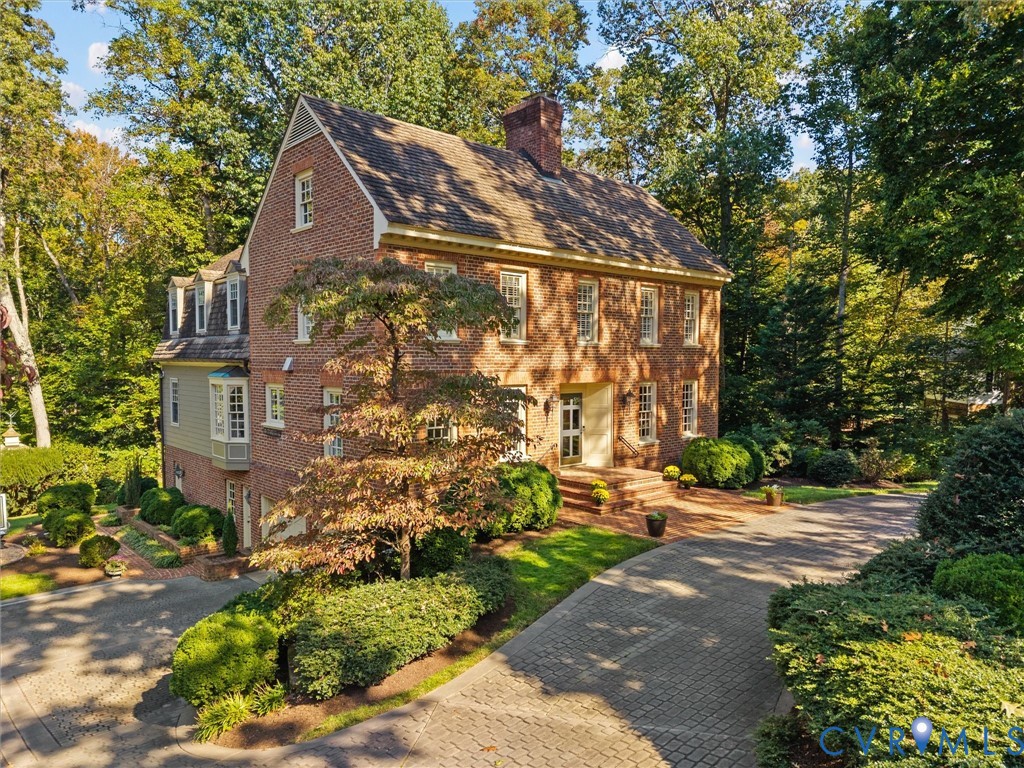 Traditional brick exterior featuring a multi-gable roofline, dormer windows, a decorative bay window, and a paved stone driveway