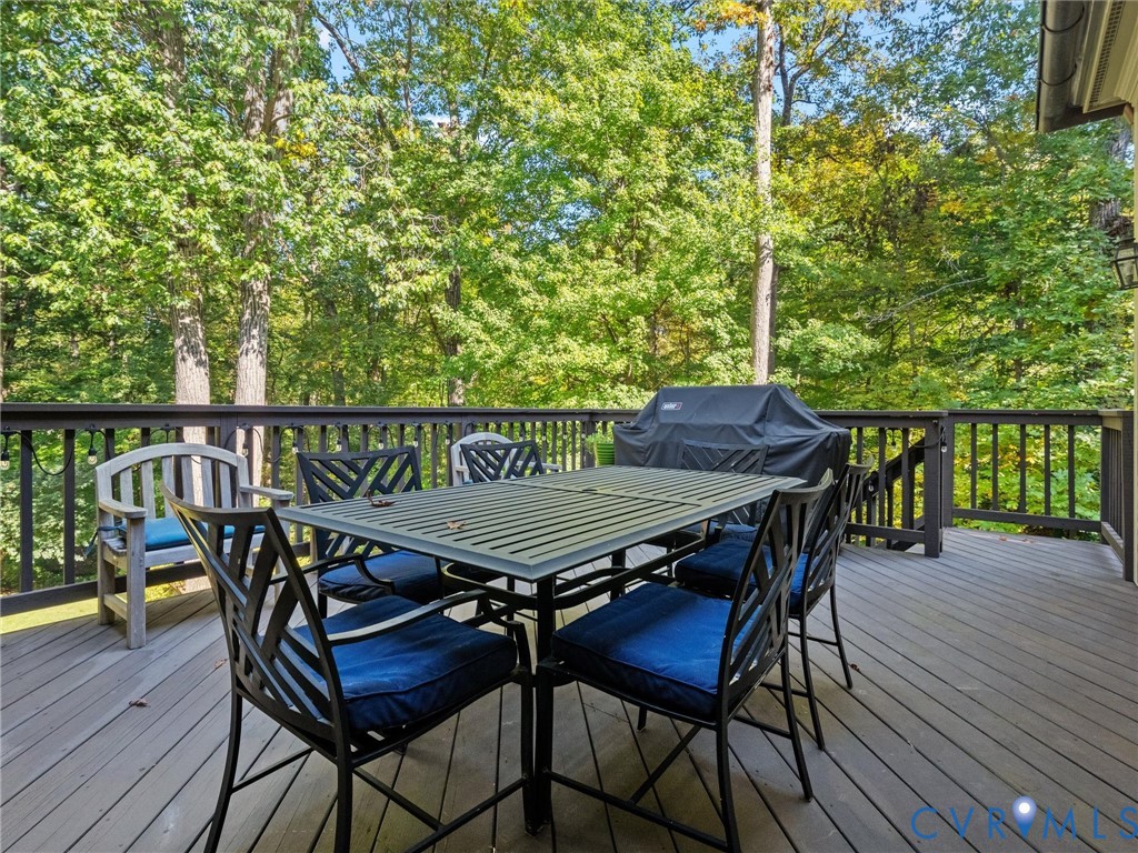 Elevated wood-plank deck featuring a dark-toned balustrade and mature woodland backdrop