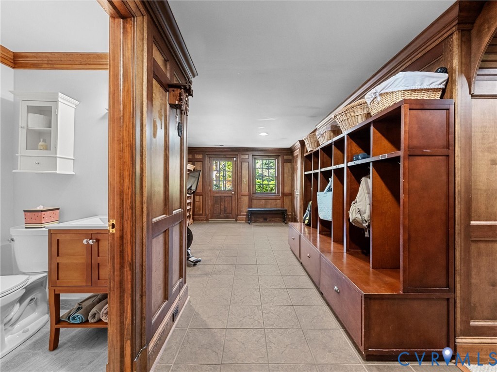 Custom wood paneling, built-in floor-to-ceiling cabinetry, tile flooring, and a vanity with a wall-mounted cabinet