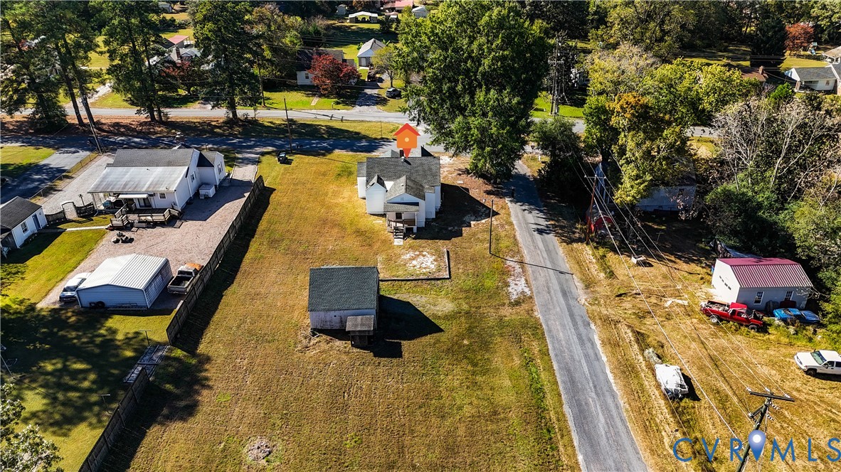 Aerial perspective of a property featuring an expansive lot, a standalone storage structure, and a residential building with a pitched shingle roof