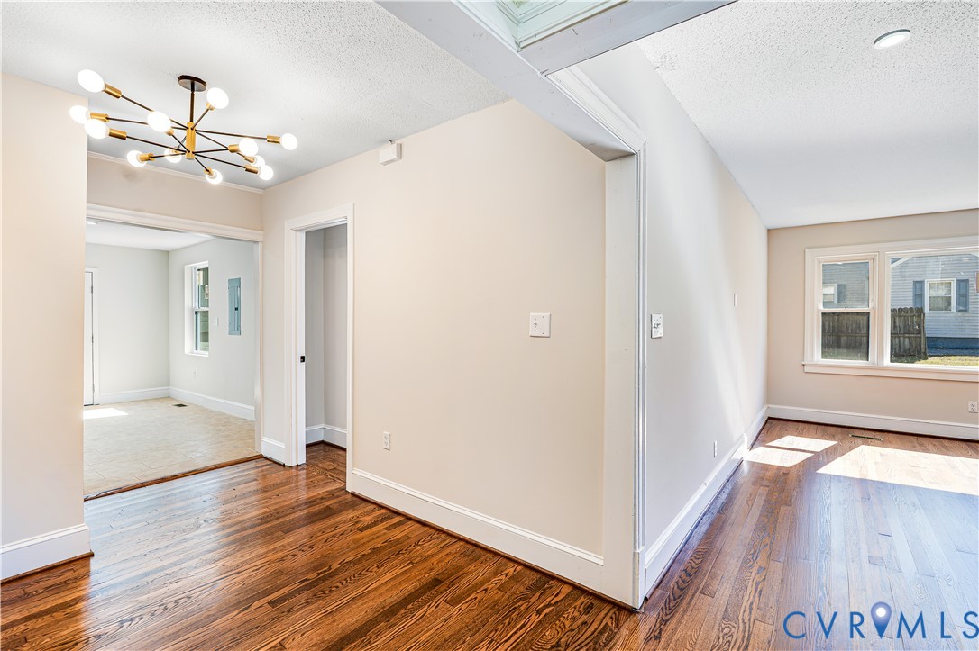 Interior featuring wood-finish flooring, a contemporary multi-arm chandelier, neutral wall paint, and double-hung windows