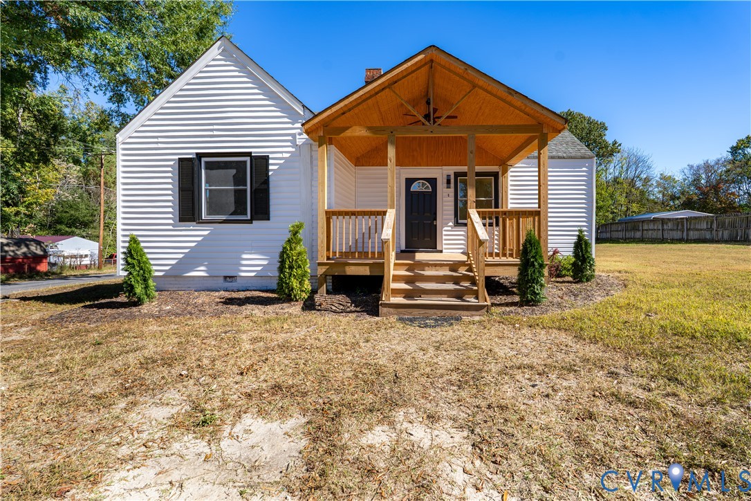 Exterior featuring white horizontal siding, dark window shutters, and a covered front porch with wood-finished ceiling and railing Exterior featuring white horizontal siding, dark window shutters, and a covered front porch with wood-finished ceiling and railing