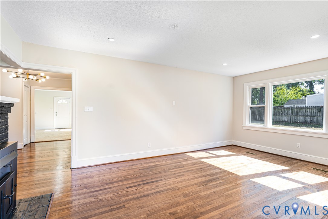 Interior space featuring wood-finish flooring, recessed lighting, a multi-light chandelier, and a black-finished stone fireplace surround