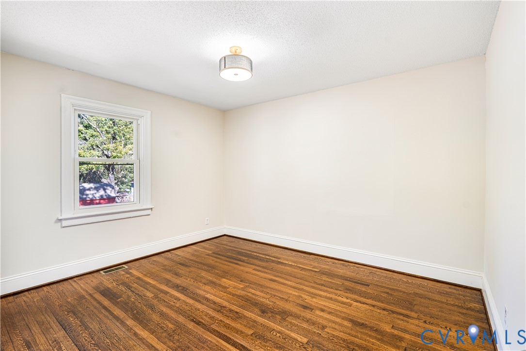 Interior room featuring wood-finish flooring, a single-hung window with casing, and a drum-style ceiling light fixture