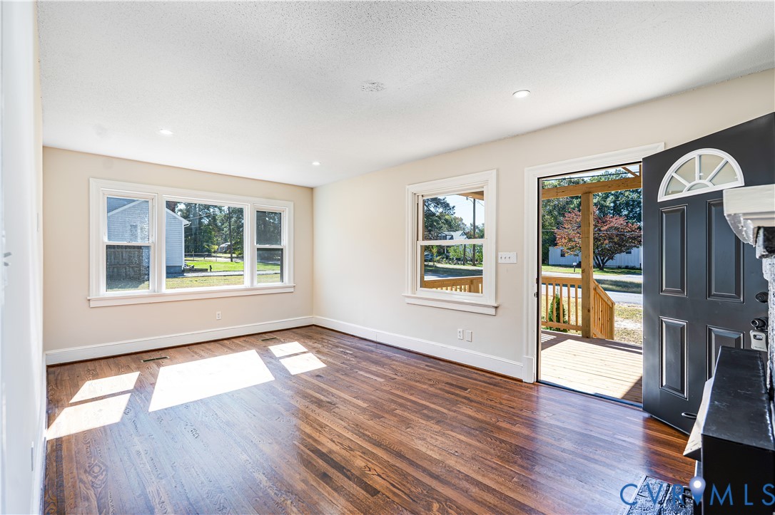 Interior space featuring wood-finish flooring, recessed lighting, multi-pane windows, and a dark-finished entry door with an arched transom window