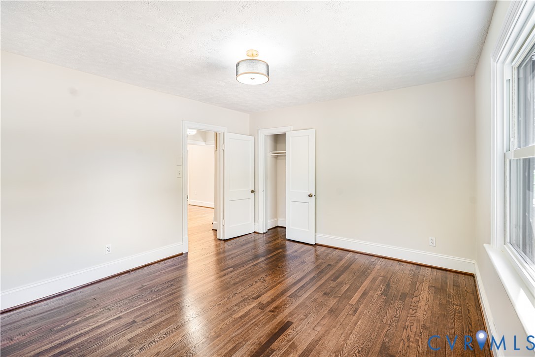 Room featuring wood-finish flooring, a drum-style ceiling light fixture, multi-panel doors, and a reach-in closet