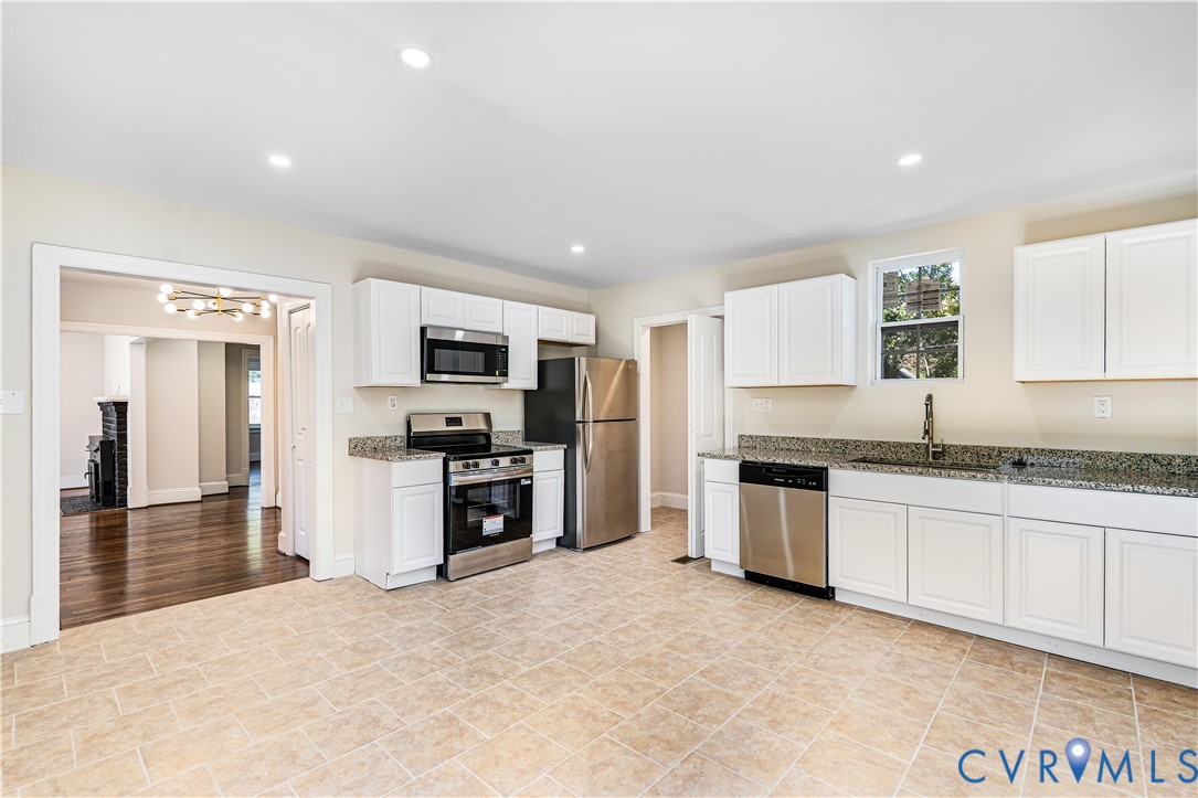 Kitchen featuring white shaker-style cabinetry, stone-finish countertops, stainless steel appliances, and tile flooring