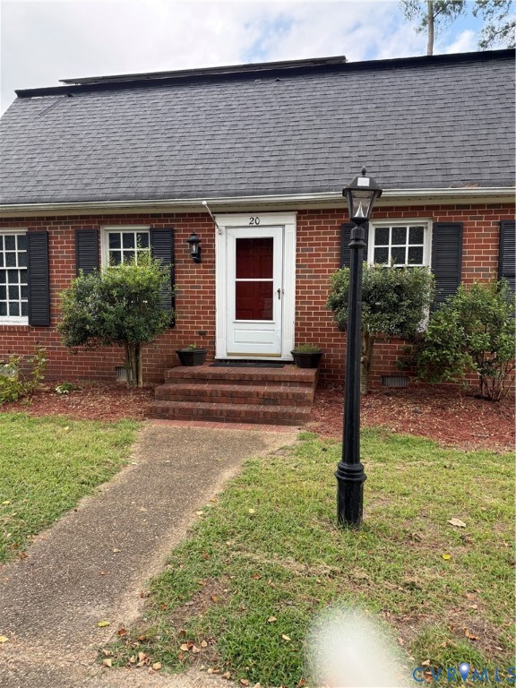 Brick exterior featuring dark shutters, a front entry with brick steps, and an integrated lamp post Brick exterior featuring dark shutters, a front entry with brick steps, and an integrated lamp post