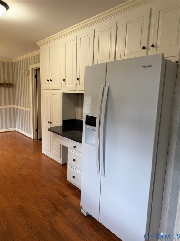 White cabinetry featuring floor-to-ceiling storage, dark solid-surface countertops, and wood-finish flooring