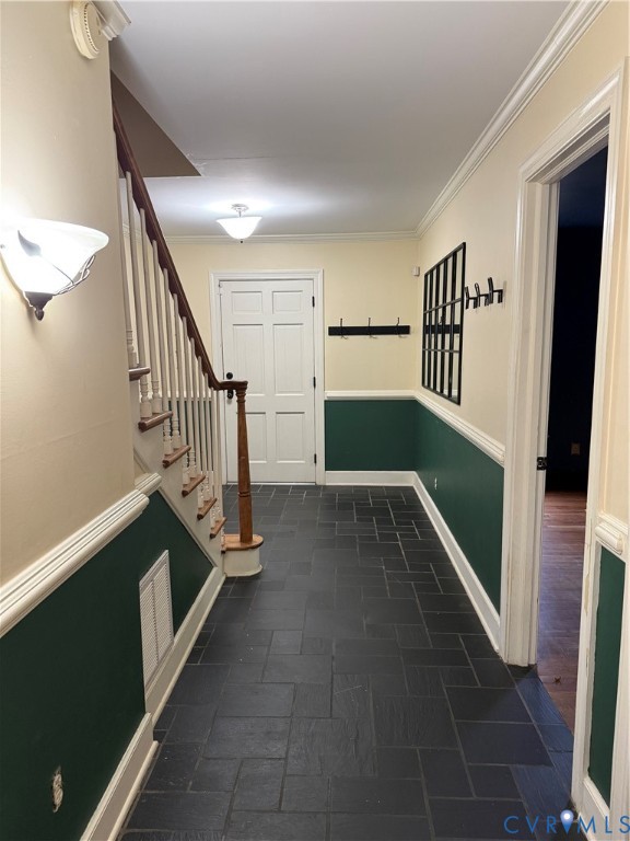 Foyer featuring slate tile flooring, wainscoting with decorative chair rail, and a staircase with stained wood handrail and white balusters