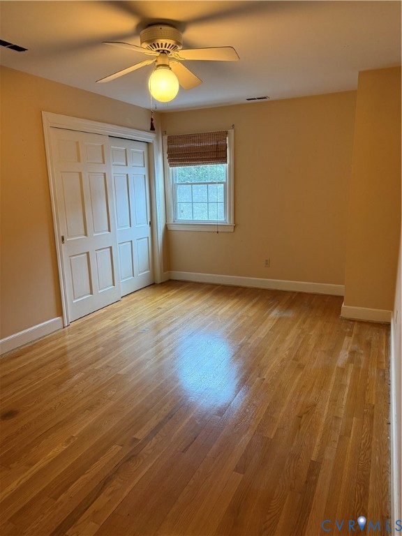Polished wood-finish flooring, multi-pane window, ceiling fan with integrated light, and paneled closet doors