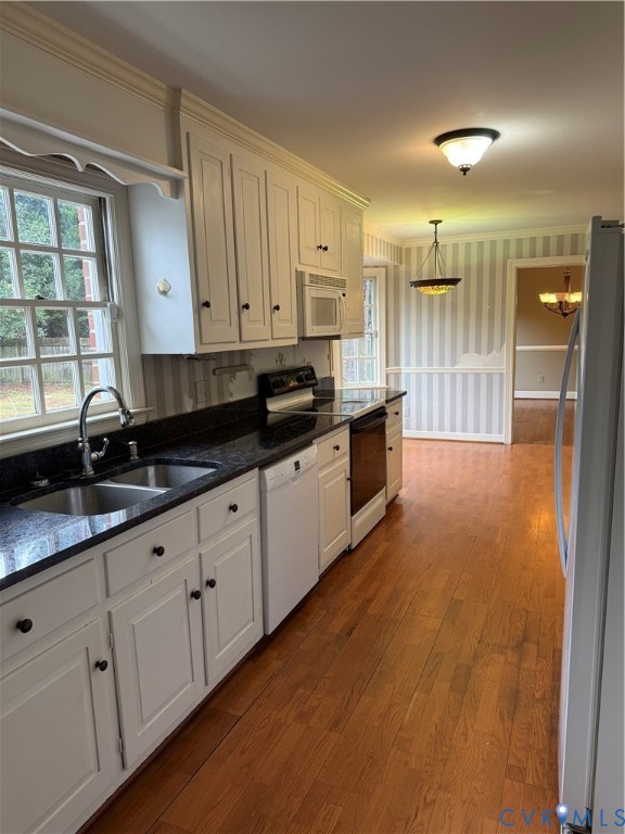 Kitchen featuring white shaker-style cabinetry, dark stone countertops, wood-finish flooring, and built-in appliances
