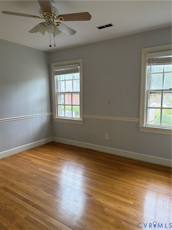 Wood-finish flooring, multi-pane windows with trim, chair rail molding, and ceiling fan with light fixture