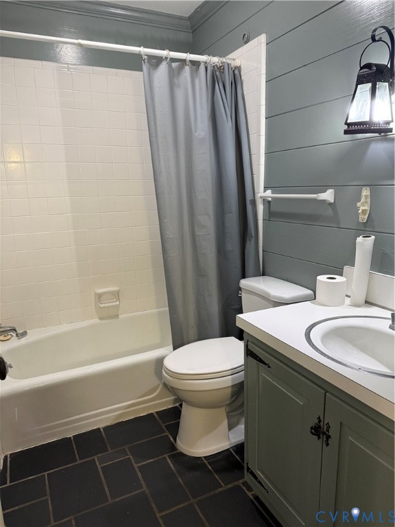 First Floor Bathroom featuring horizontal plank wall paneling, vanity with integrated basin and countertop, tiled tub surround, and dark-toned floor tile