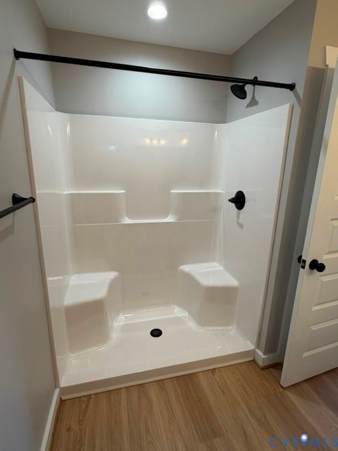 White shower surround featuring integrated seating, matte black plumbing fixtures, and a coordinating matte black shower rod