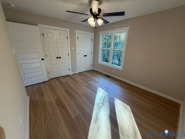Wood-finish flooring, multi-panel doors, double-closet configuration, and a central ceiling fan with integrated lighting