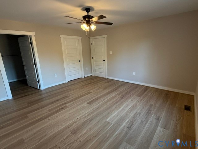 Neutral-toned interior featuring wood-finish flooring, a multi-light ceiling fan, and five-panel interior doors