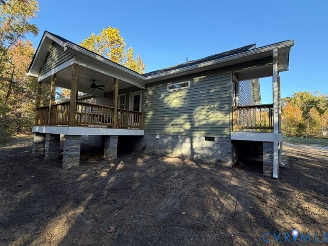 Exterior featuring horizontal siding, a raised deck with wooden railing, a covered porch with a ceiling fan, and a concrete block foundation