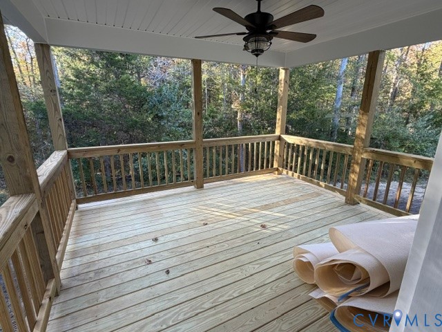 Covered porch featuring wood decking, wood railing, beadboard ceiling, and a ceiling fan with integrated light fixture