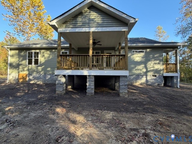 Exterior featuring green horizontal siding, a covered wooden deck with a built-in ceiling fan, and a masonry foundation with stacked stone pillars