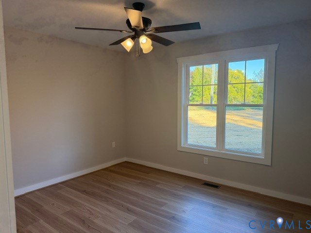 Room featuring wood-finish flooring, a multi-light ceiling fan, and a dual-pane window with interior trim