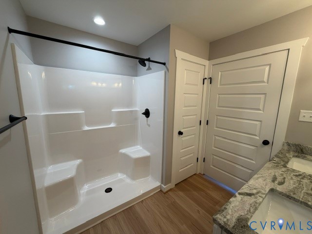 Walk-in shower with integrated seating and matte black hardware, dual-sink vanity with patterned stone countertop, and five-panel interior doors