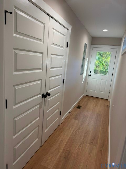 Wood-finish flooring, white five-panel interior doors with matte black hardware, and an exterior door featuring a glass inset and matching matte black hardware