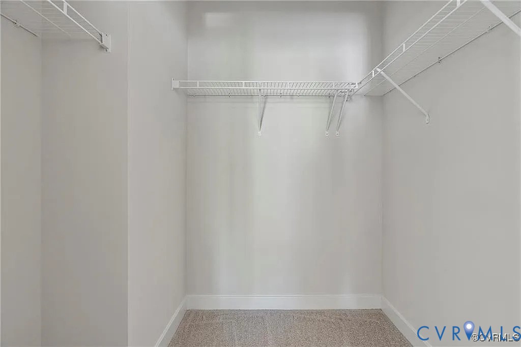 Walk-in closet featuring neutral carpeting and installed white wire shelving Walk-in closet featuring neutral carpeting and installed white wire shelving