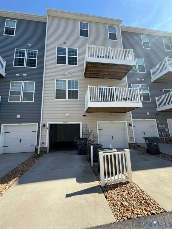 Three-story townhome exterior featuring horizontal vinyl siding, private elevated balconies with white railings, and integrated garage parking