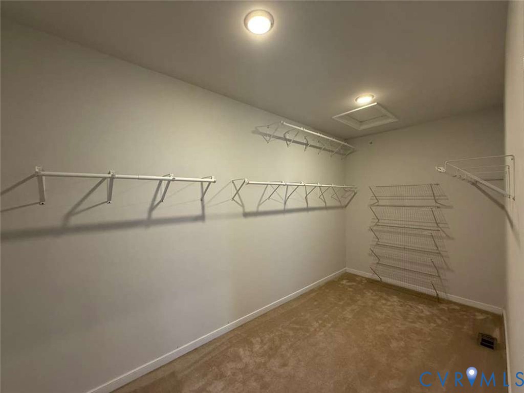 Walk-in closet featuring wall-to-wall carpeting, multiple levels of white wire shelving, and overhead flush-mount lighting