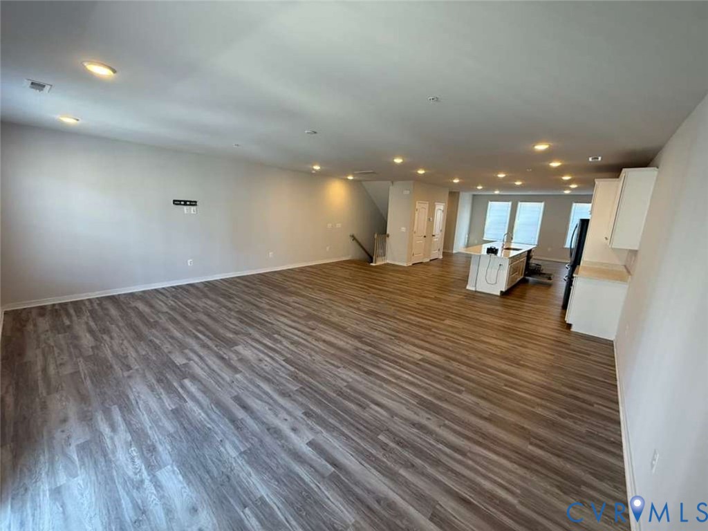 Open-concept interior featuring wood-finish flooring, recessed lighting, and a kitchen island with a built-in sink