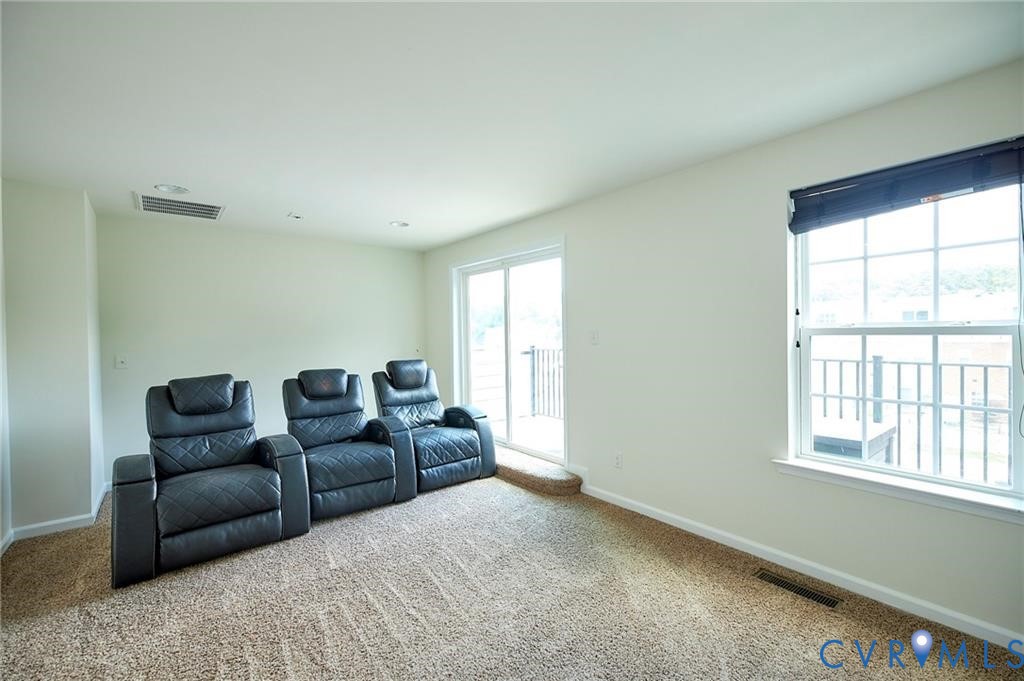 Interior space featuring neutral wall tones, wall-to-wall carpeting, recessed ceiling lighting, a single-hung window with a blind, and a sliding glass door providing external access