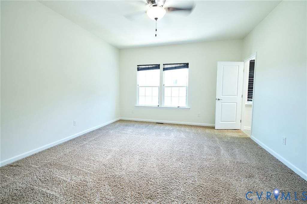 Neutral-toned carpeting, dual-pane windows, and a central ceiling fan with integrated lighting fixture