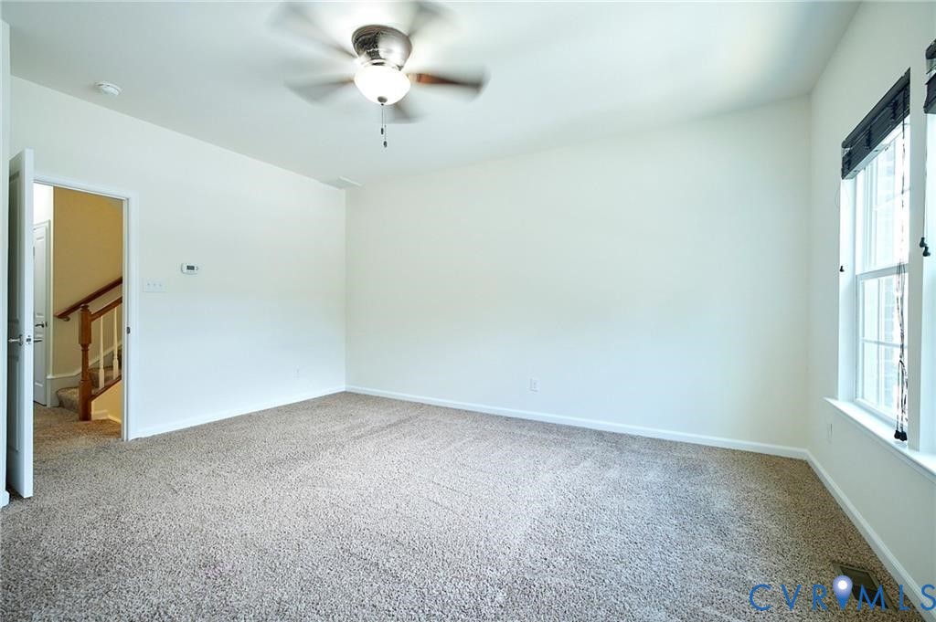 Neutral-toned carpeting, ceiling fan with integrated lighting, and window with dark-toned frame
