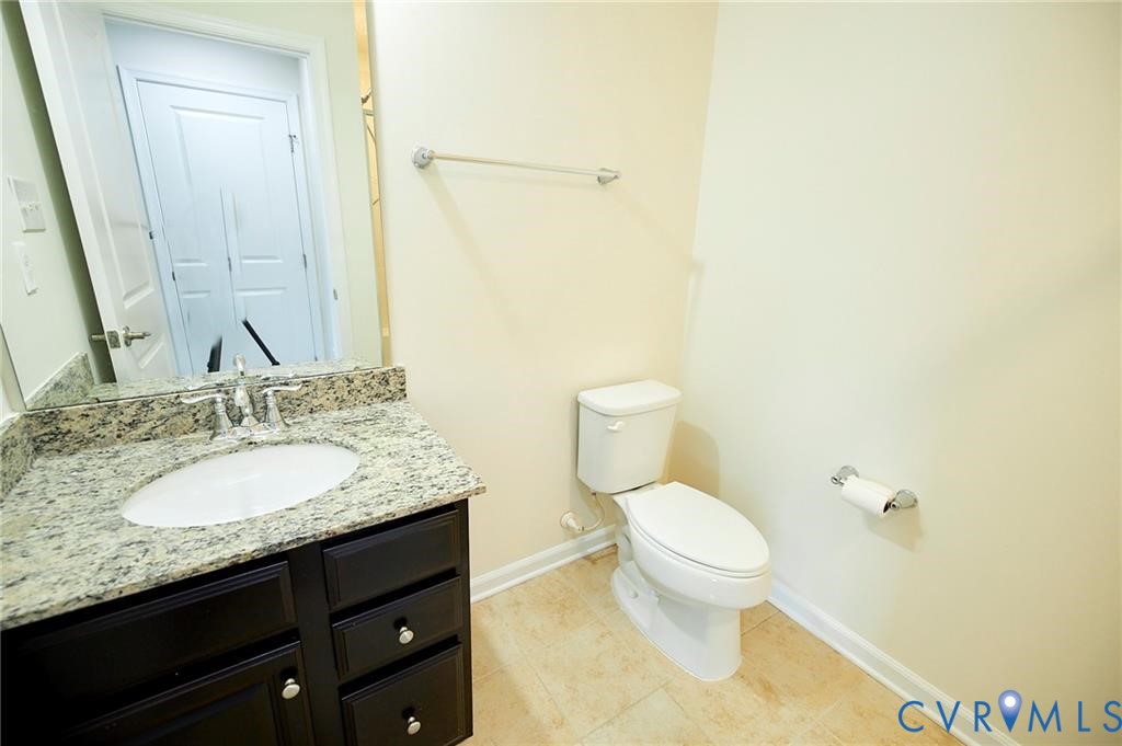 Dark-finish vanity cabinetry with stone-patterned countertop, integrated porcelain sink, chrome faucet, and tile flooring