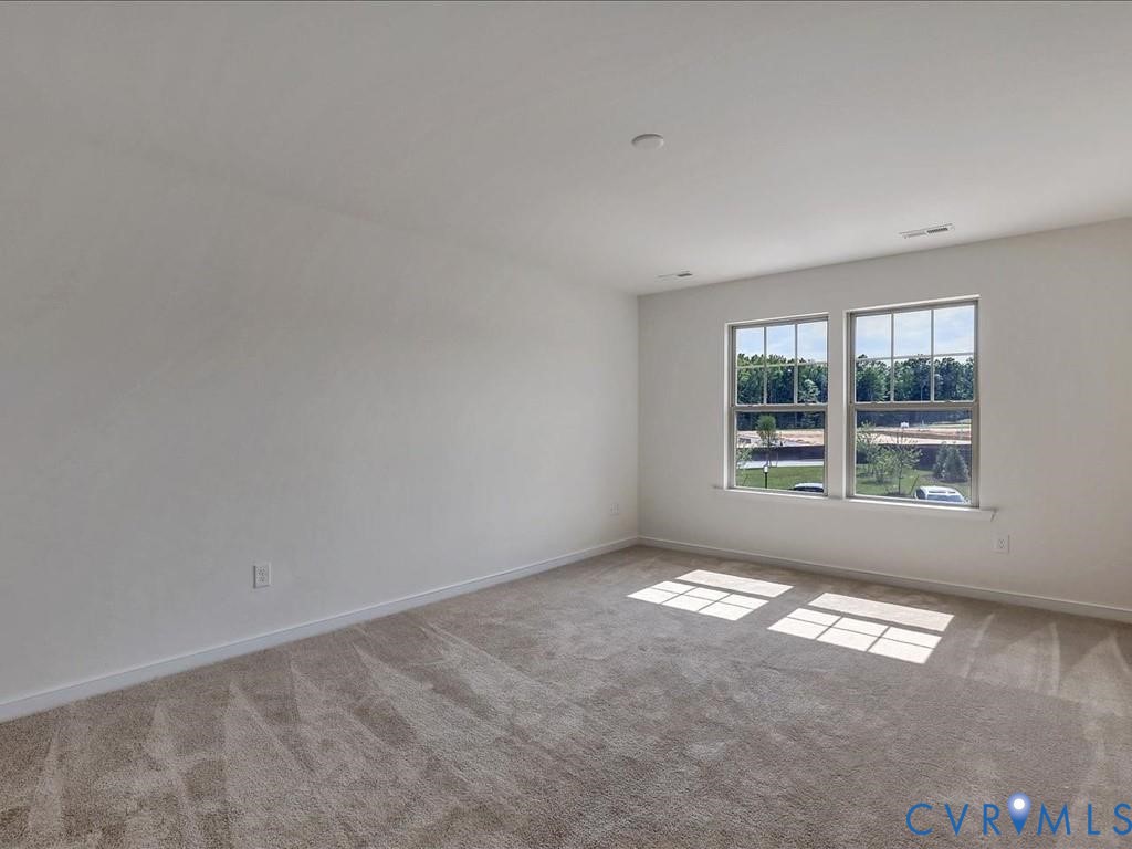 Neutral-toned interior space featuring light-colored wall-to-wall carpeting and dual-pane windows with grid detailing Neutral-toned interior space featuring light-colored wall-to-wall carpeting and dual-pane windows with grid detailing