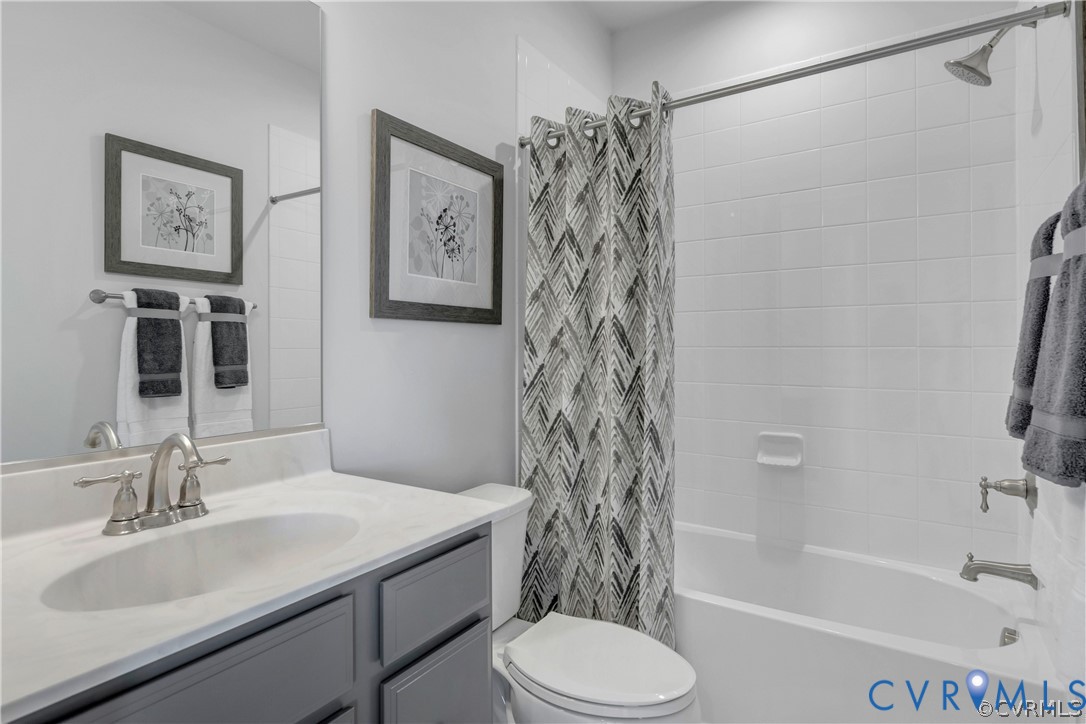 Bathroom featuring a vanity with stone-finish countertop, undermount sink, brushed nickel faucet, tub-shower combination with white wall tile, and frameless wall-mounted mirror