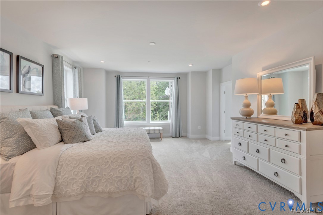 Neutral wall-to-wall carpeting, recessed ceiling lighting, and large windows with natural illumination