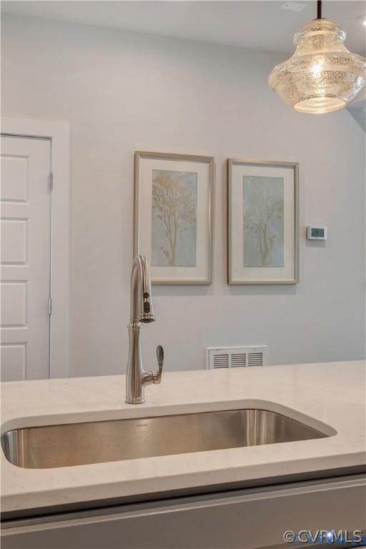 Undermount stainless steel kitchen sink featuring a high-arc pull-down faucet, set within a solid-surface countertop and complemented by a textured glass pendant light fixture Undermount stainless steel kitchen sink featuring a high-arc pull-down faucet, set within a solid-surface countertop and complemented by a textured glass pendant light fixture