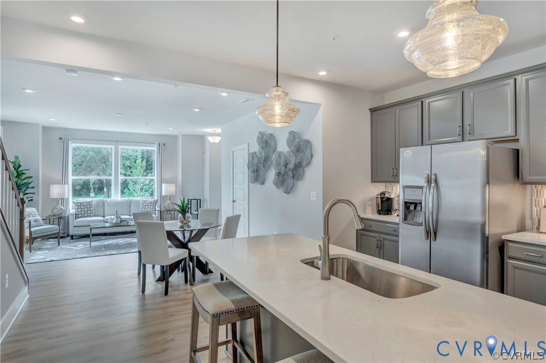 Kitchen island with quartz countertop and stainless steel under-mount sink, complemented by shaker-style cabinetry and multi-light pendant fixtures Kitchen island with quartz countertop and stainless steel under-mount sink, complemented by shaker-style cabinetry and multi-light pendant fixtures