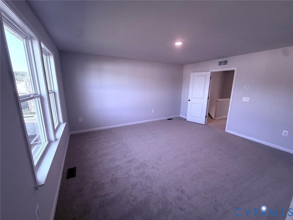 Neutral-toned interior featuring plush carpeting, multiple paneled windows, recessed lighting, and a solid-core interior door