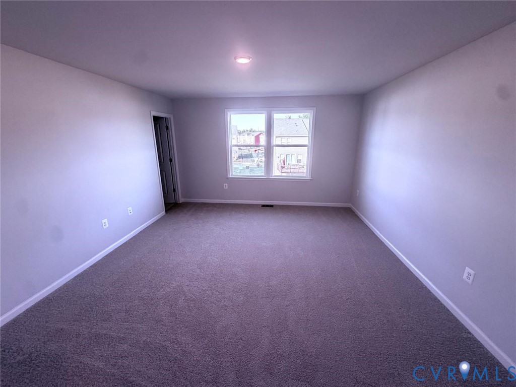 Neutral-toned interior featuring wall-to-wall carpeting, expansive painted walls, and a dual-pane window with white trim
