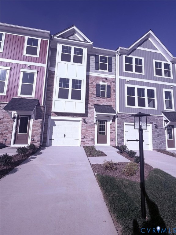 Multi-story exterior featuring stone veneer, vertical siding, multi-paned windows, and integrated garage access Multi-story exterior featuring stone veneer, vertical siding, multi-paned windows, and integrated garage access